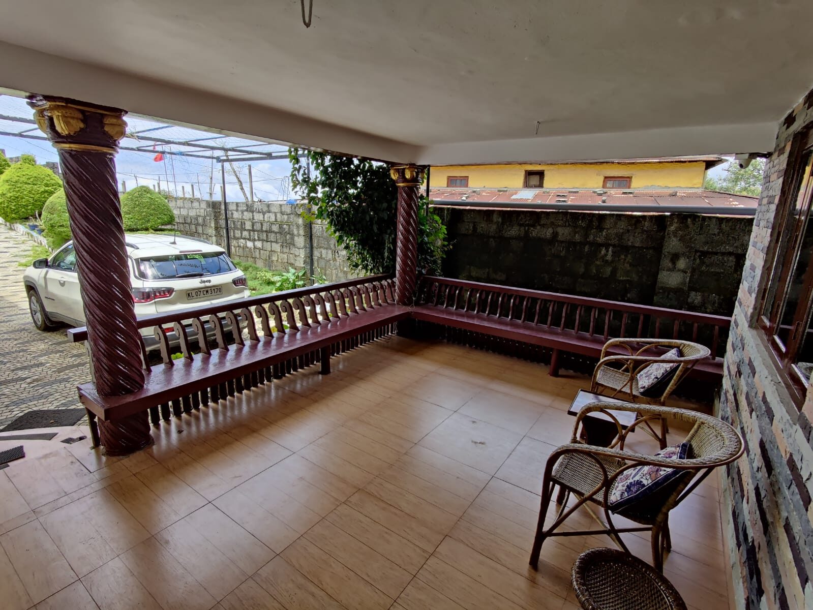 Covered veranda with chairs and tiled flooring